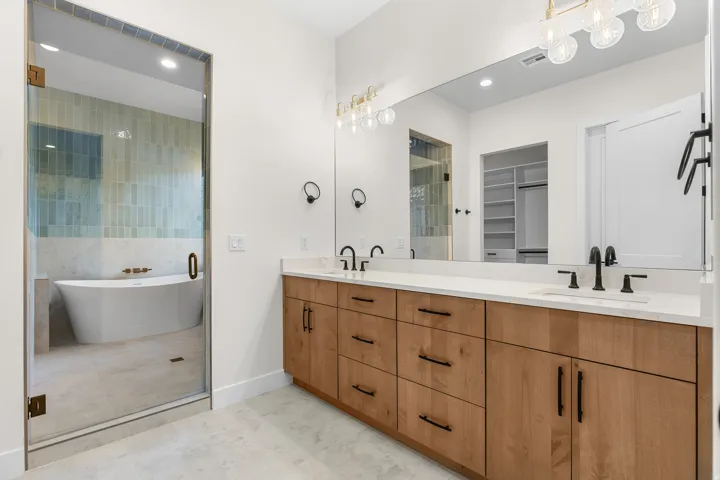 Full bath with double vanity, a freestanding tub, a spacious closet, recessed lighting, and light tile patterned floors