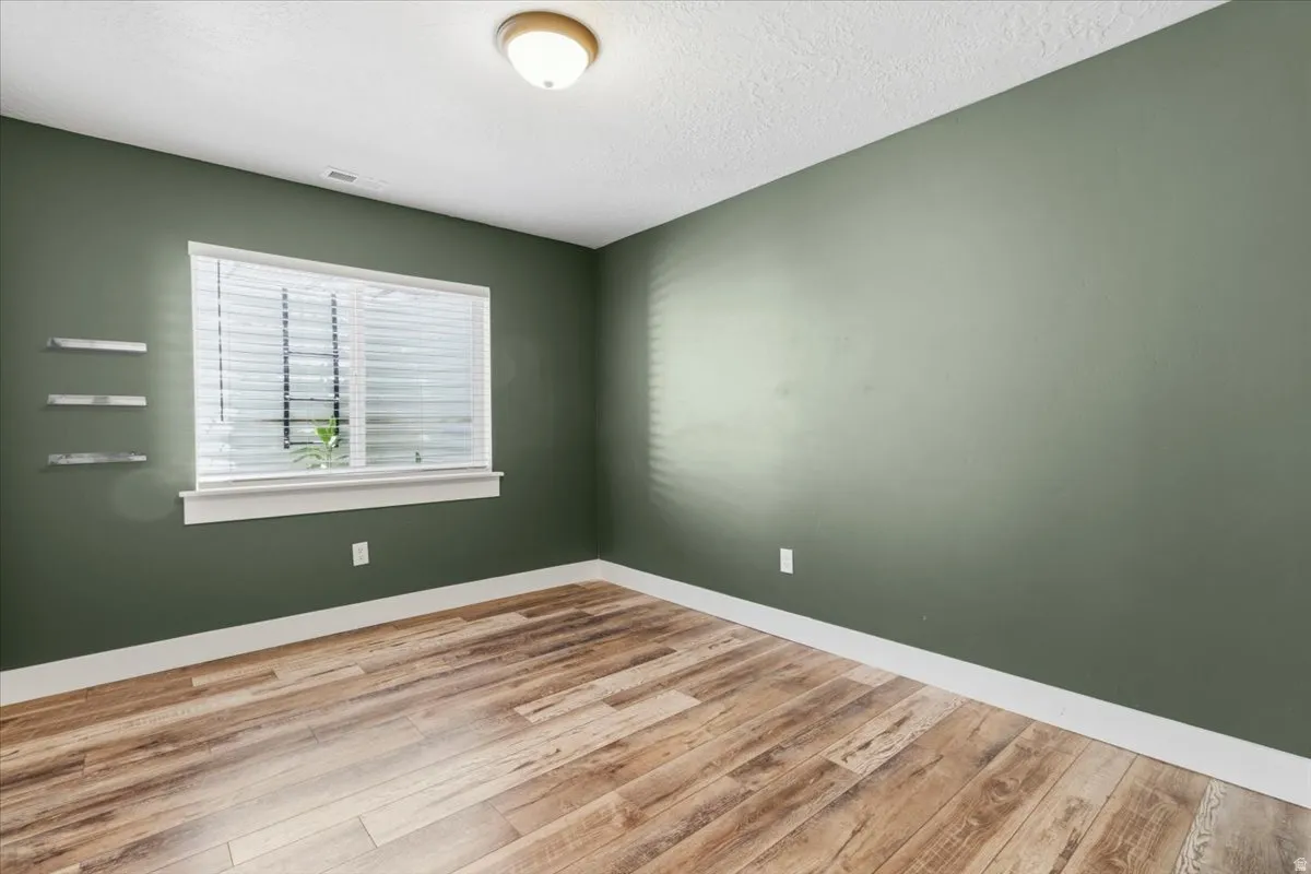 Empty room with light wood-type flooring and a textured ceiling