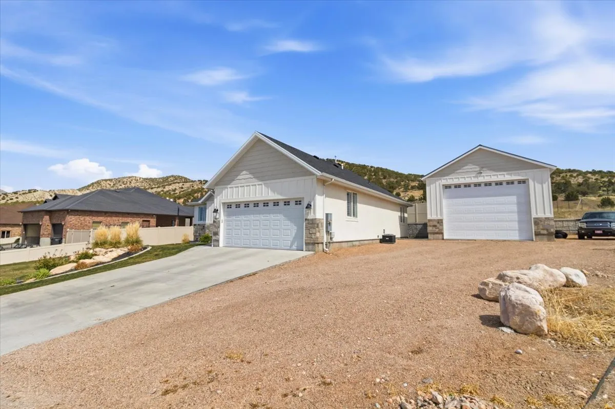Ranch-style house with stone siding, a detached garage, board and batten siding, a mountain view, and an outdoor structure