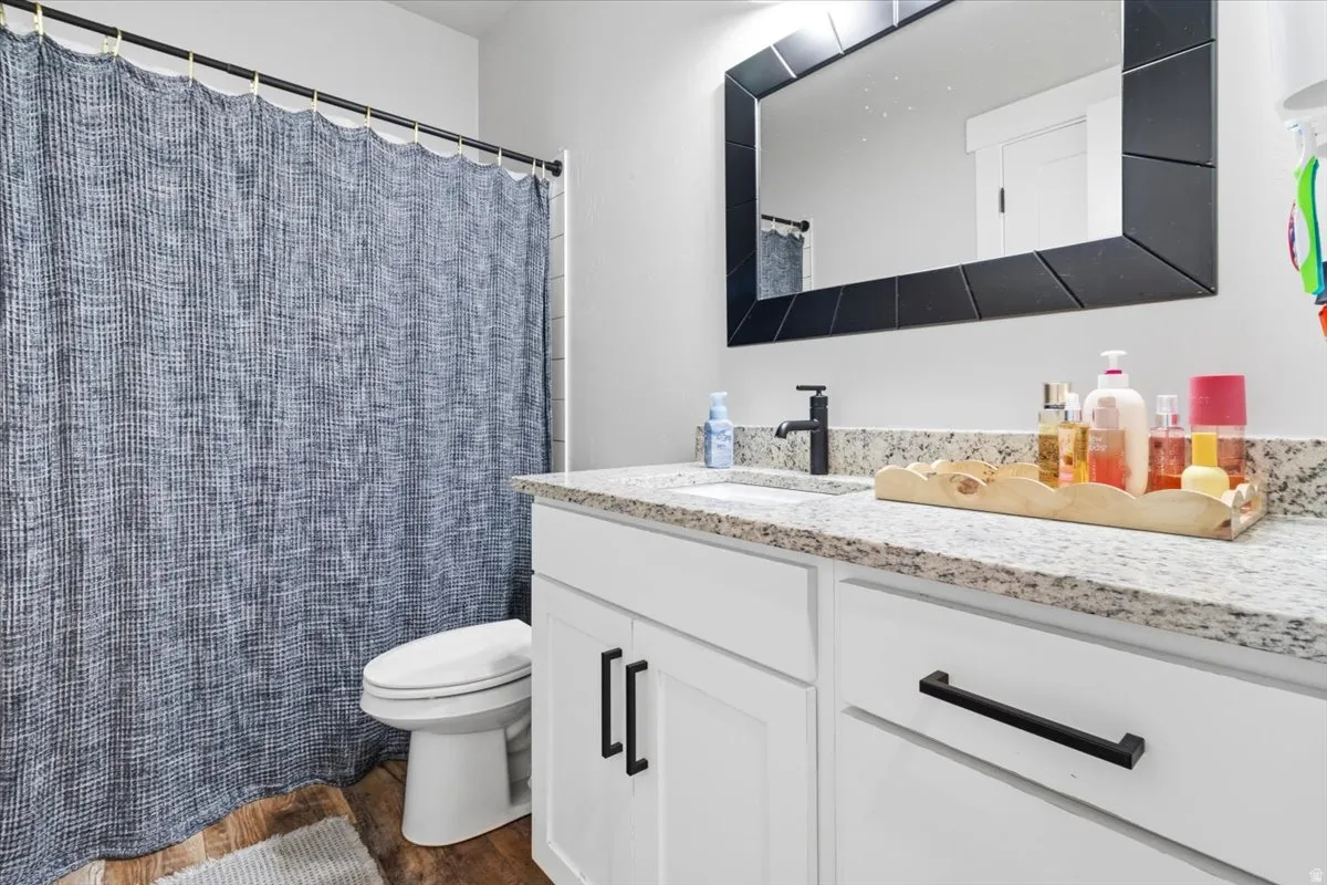 Bathroom with vanity, a shower with shower curtain, and dark wood finished floors