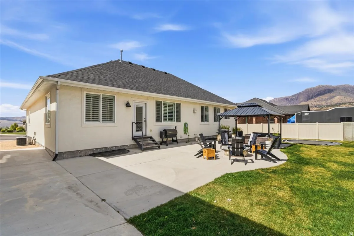 Rear view of property with a mountain view, a gazebo, stucco siding, and roof with shingles