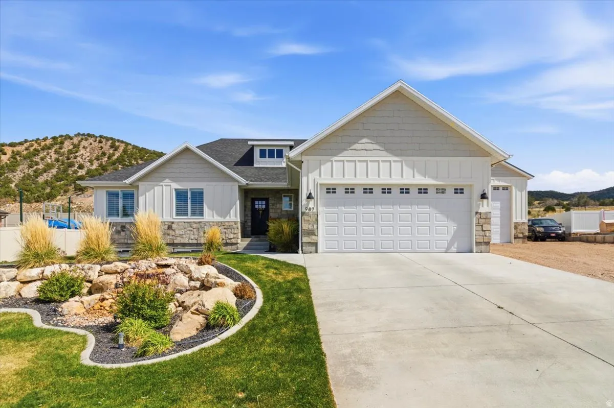 View of front of home featuring board and batten siding, a mountain view, stone siding, an attached garage, and driveway