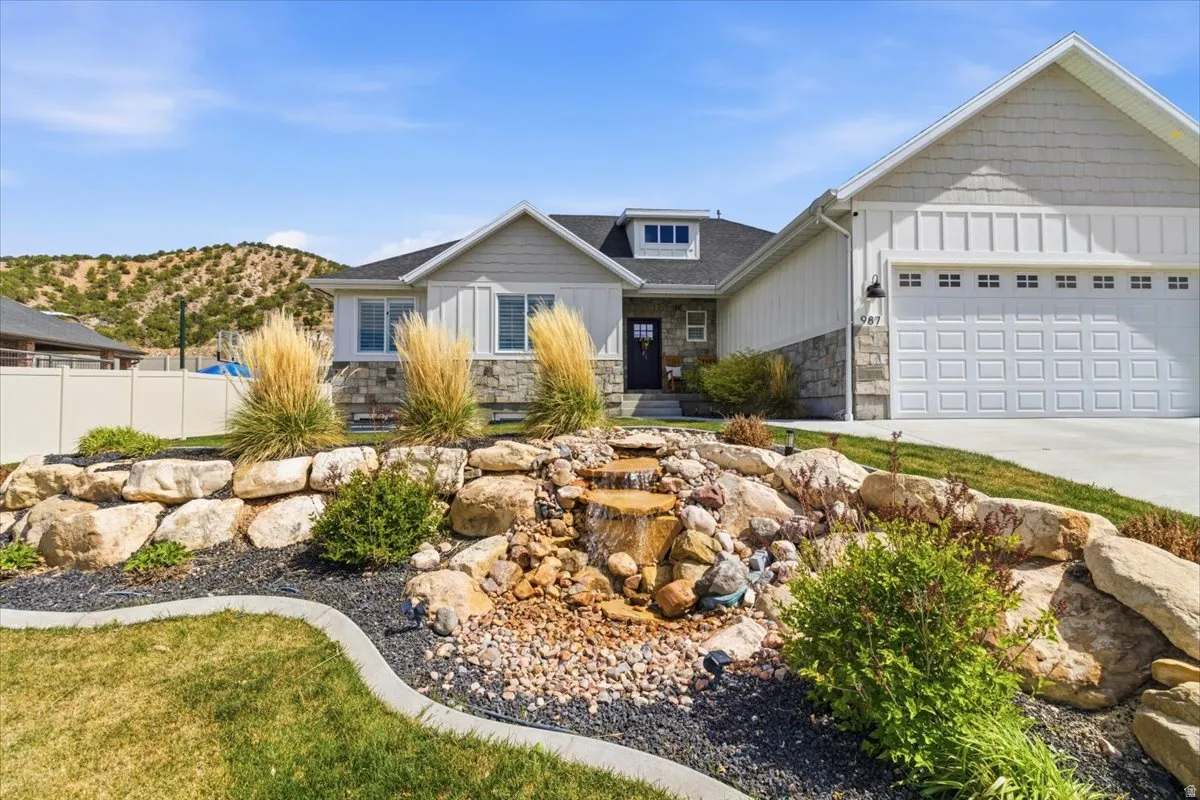 Craftsman-style home with stone siding, board and batten siding, an attached garage, driveway, and a mountain view