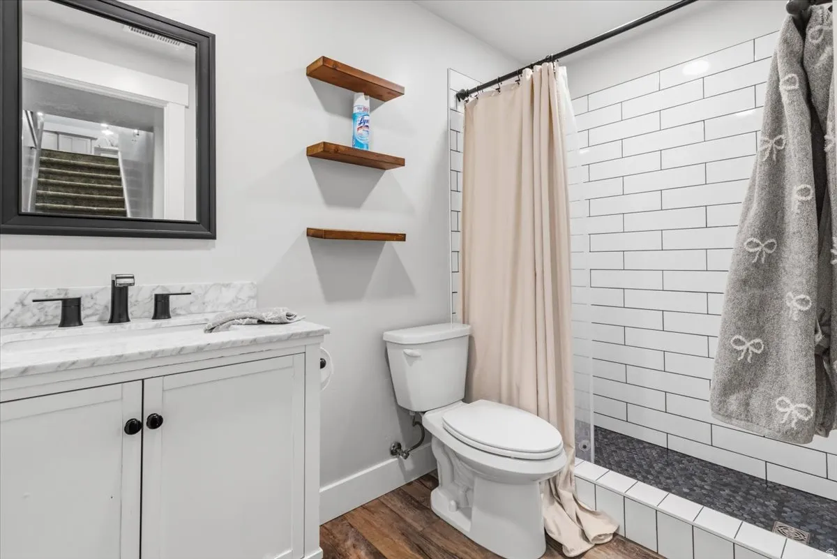 Full bath featuring vanity, a stall shower, and dark wood-style flooring