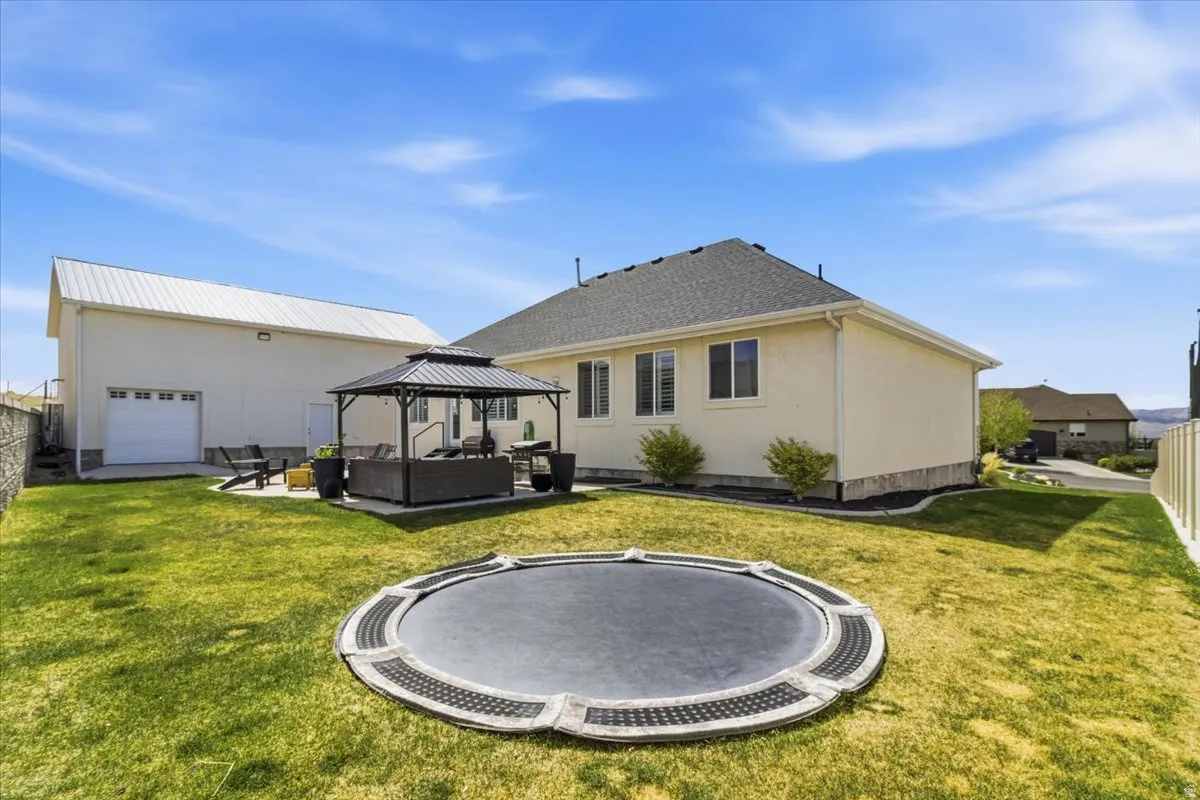 Back of house featuring a gazebo, an outdoor lounge area, a patio, a trampoline, and stucco siding