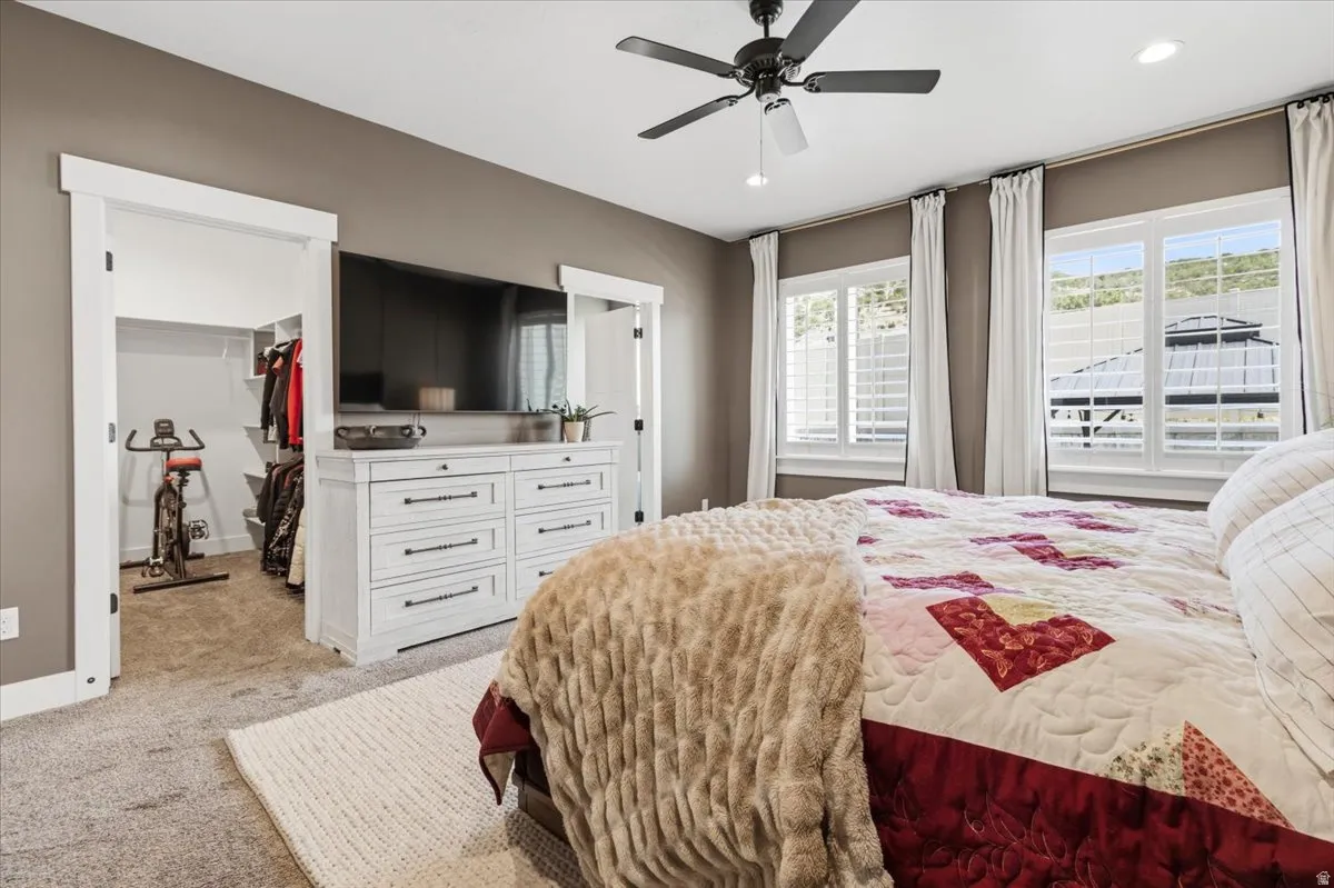 Bedroom with light carpet, a spacious closet, a ceiling fan, and recessed lighting