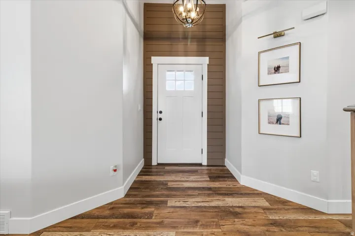 Entryway with wooden walls, suspended lighting, and wood finished floors