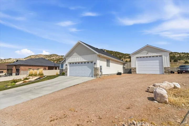 Ranch-style house with stone siding, a detached garage, board and batten siding, a mountain view, and an outdoor structure