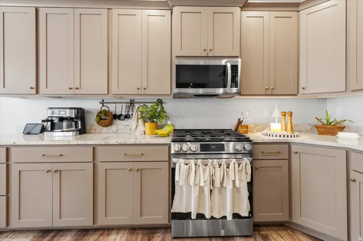 Kitchen featuring stainless steel appliances, light stone countertops, light wood-type flooring, and gray cabinetry