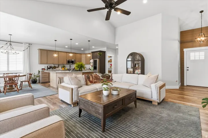 Living area with hanging lights, healthy amount of natural light, light wood-style floors, and lofted ceiling