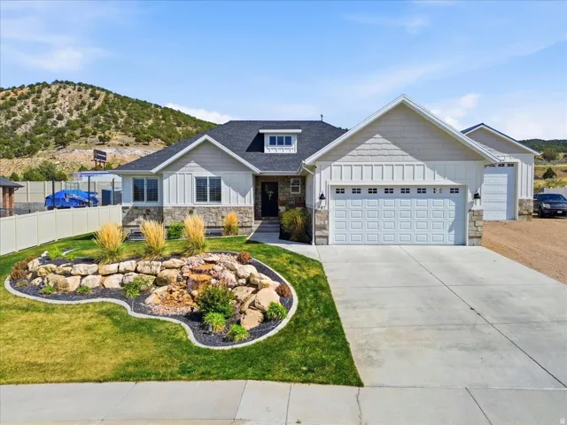 Craftsman-style home with board and batten siding, stone siding, an attached garage, driveway, and a mountain view
