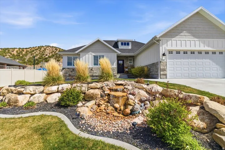 Craftsman-style home with stone siding, board and batten siding, an attached garage, driveway, and a mountain view