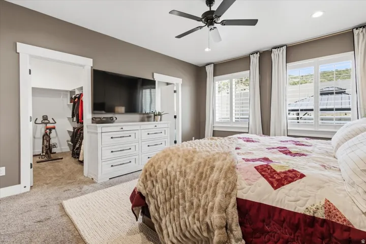 Bedroom with light carpet, a spacious closet, a ceiling fan, and recessed lighting