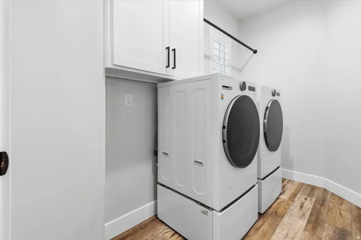 Laundry area with light wood finished floors, washing machine and clothes dryer, and cabinet space