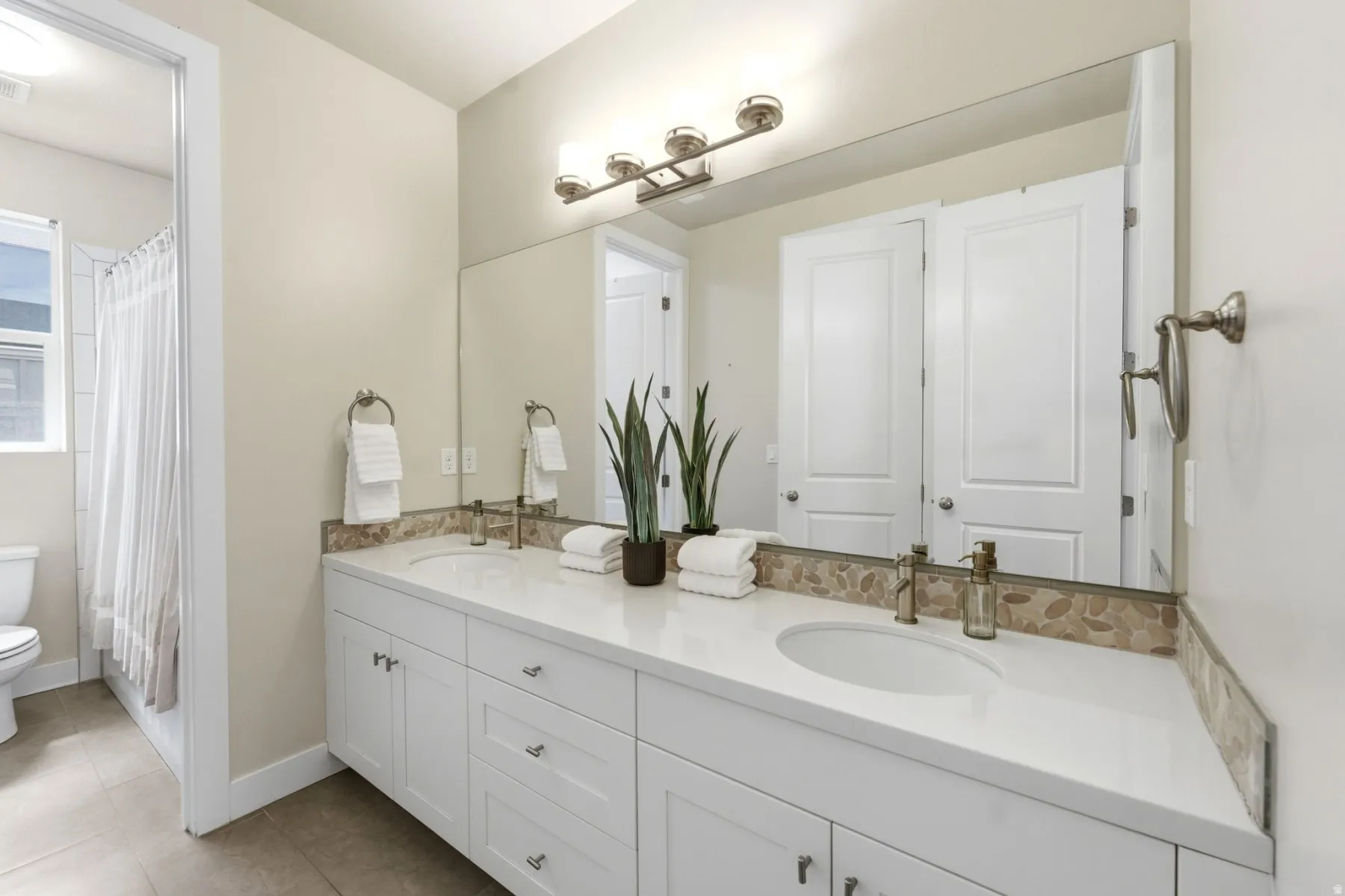 Full bath featuring double vanity, light tile patterned flooring, and shower / tub combo