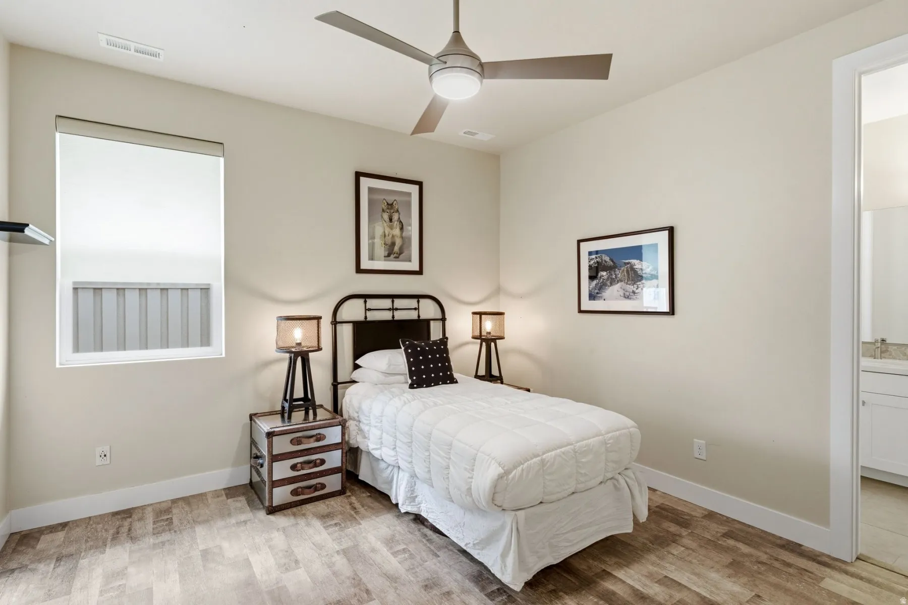 Bedroom with light wood-style flooring, a ceiling fan, and ensuite bathroom