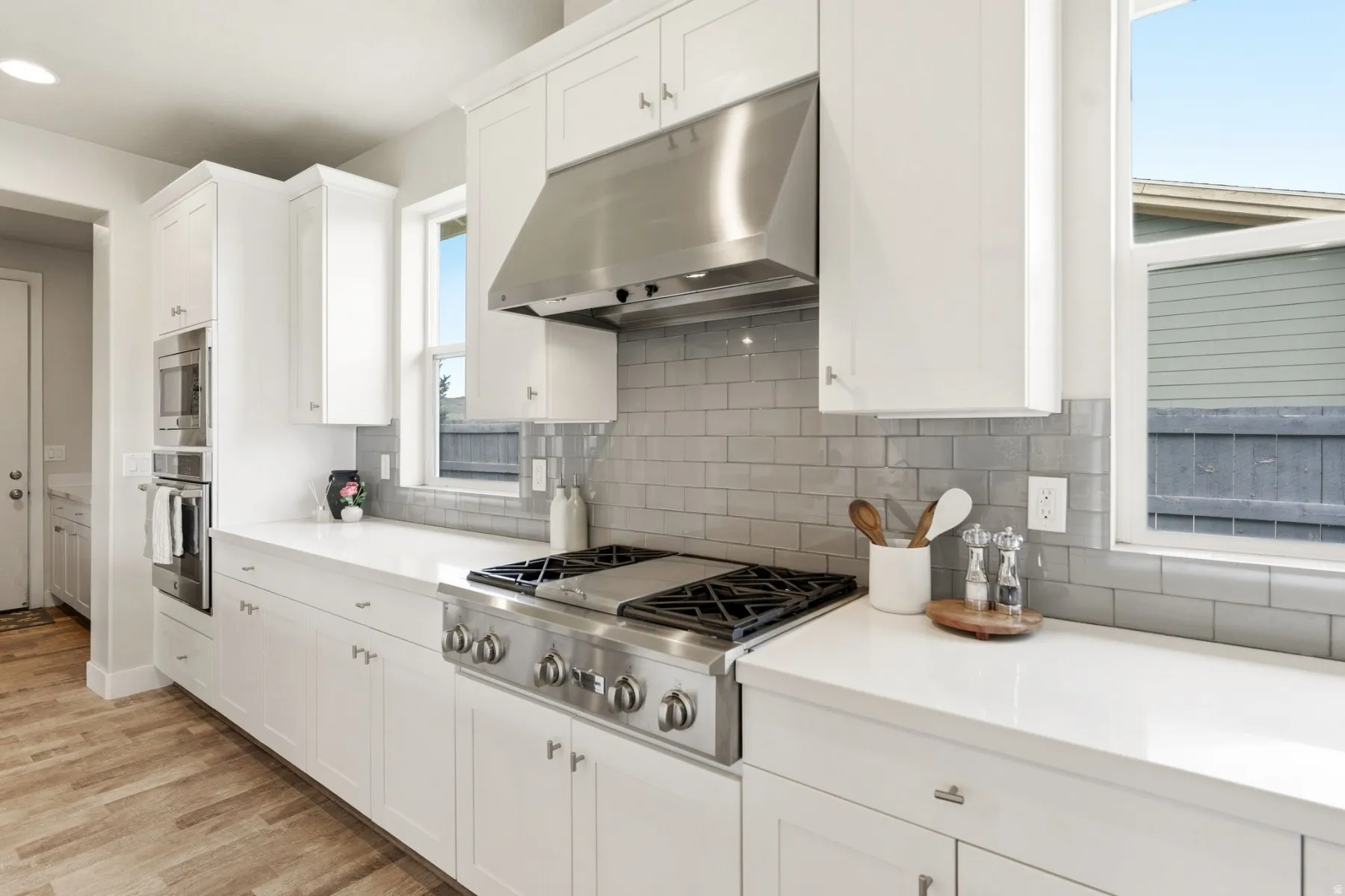Kitchen featuring white cabinetry, stainless steel appliances, light wood-style floors, and backsplash
