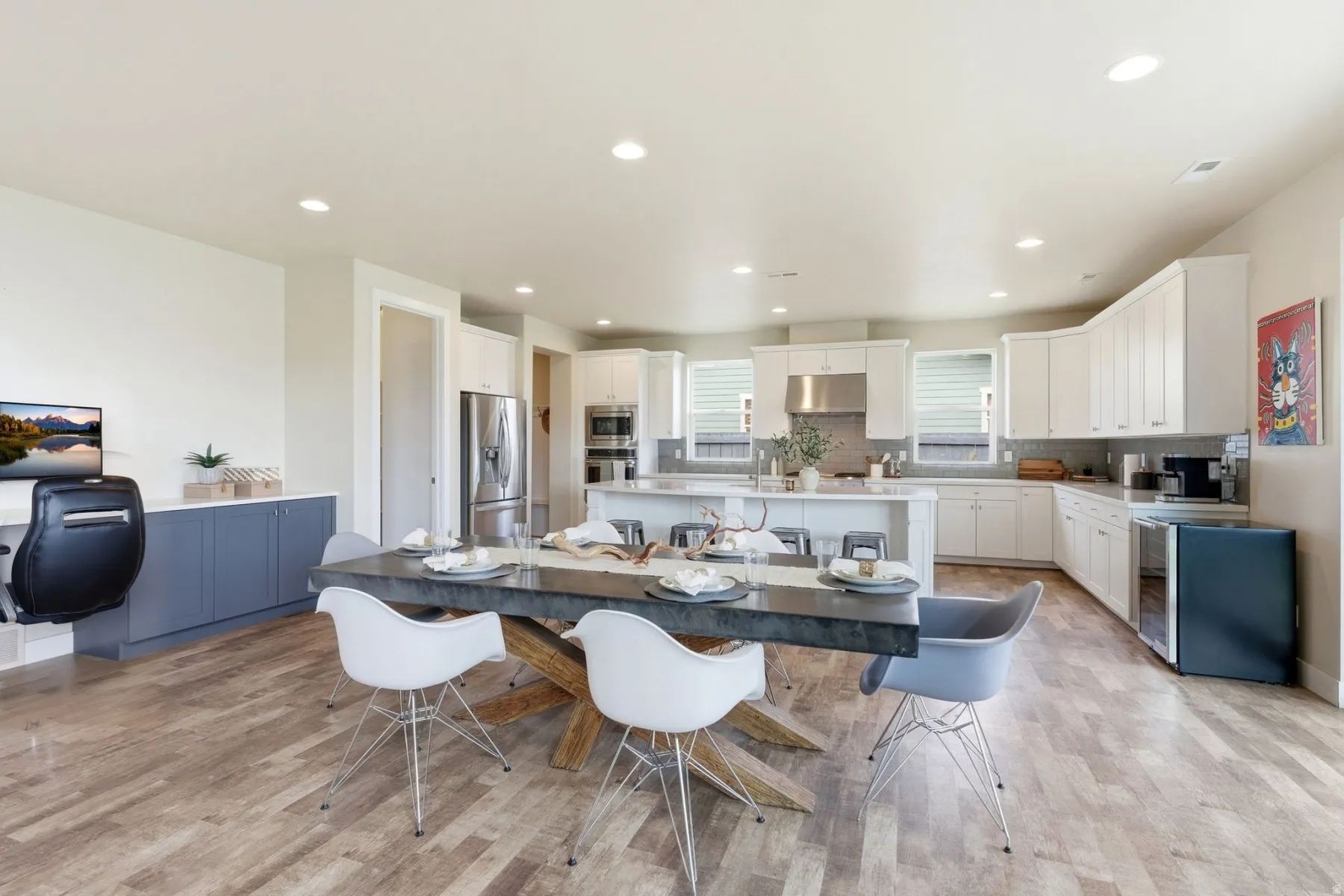 Kitchen with a center island with sink, white cabinets, stainless steel appliances, light wood-style floors, and a breakfast bar