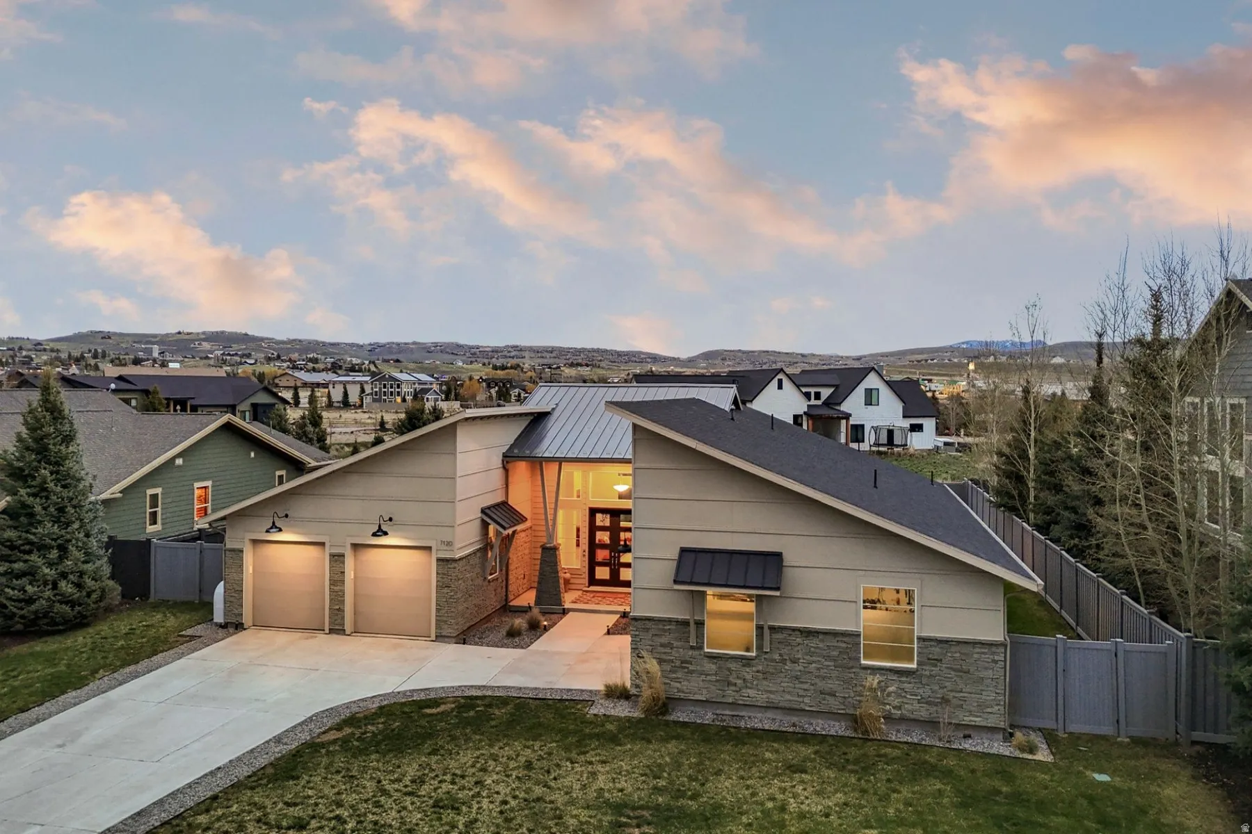 Contemporary house featuring concrete driveway, a garage, stone siding, and a residential view