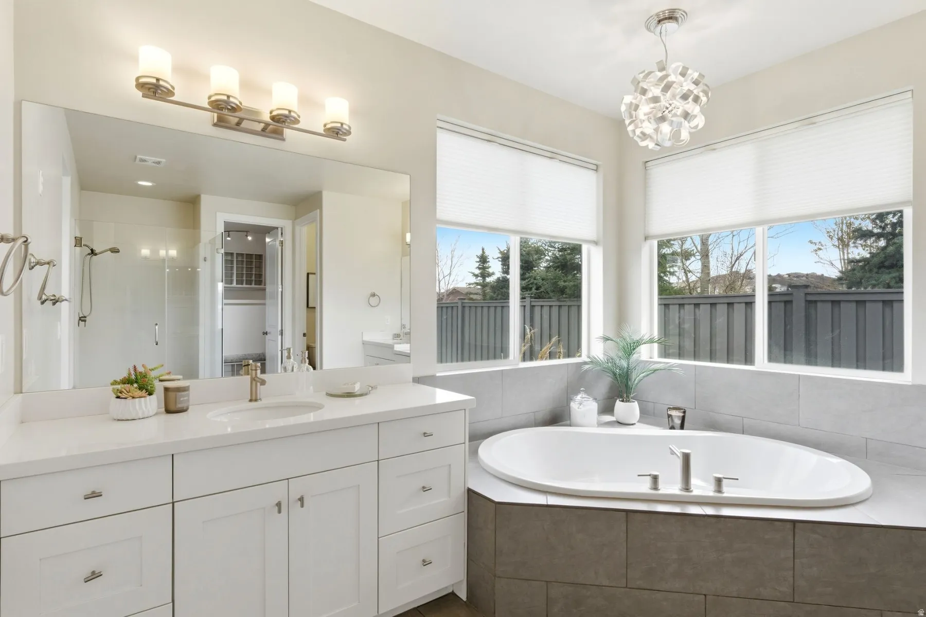 Bathroom featuring a shower stall, vanity, a garden tub, and a chandelier