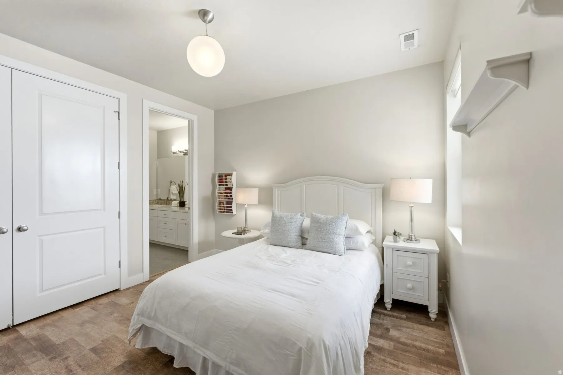 Bedroom with ensuite bath and wood finished floors