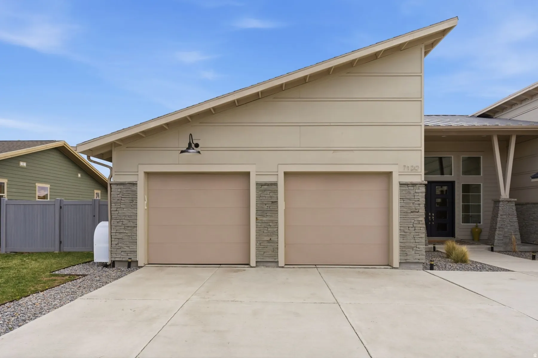View of front of home featuring stone siding, concrete driveway, an attached garage, and covered porch