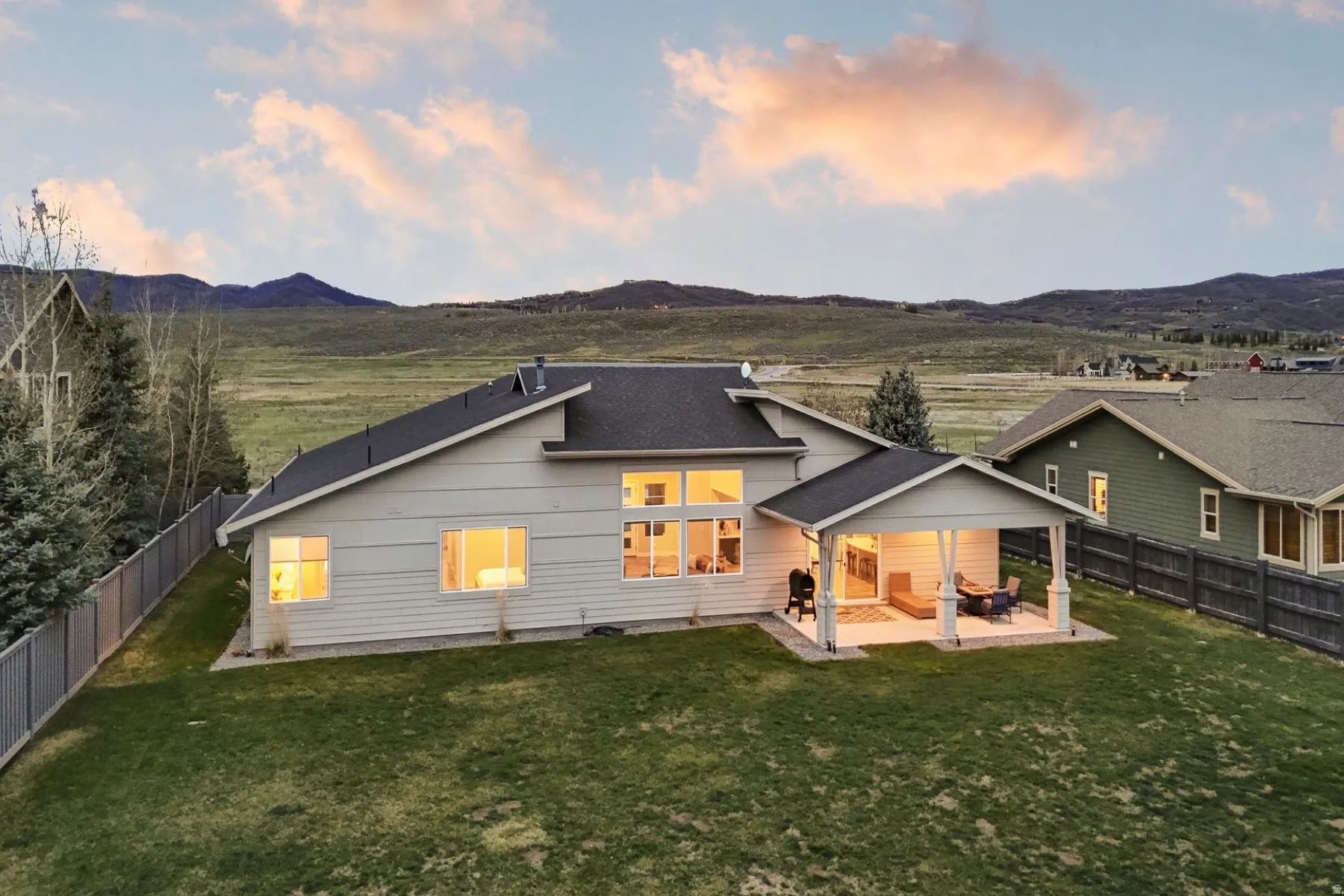 Back of property at dusk with a patio area, a fenced backyard, and a mountain view