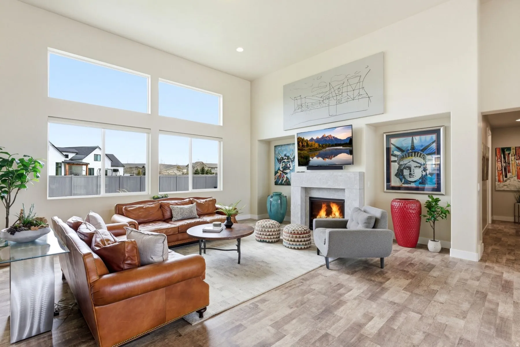 Living area featuring a high ceiling, a warm lit fireplace, light wood-style floors, and recessed lighting