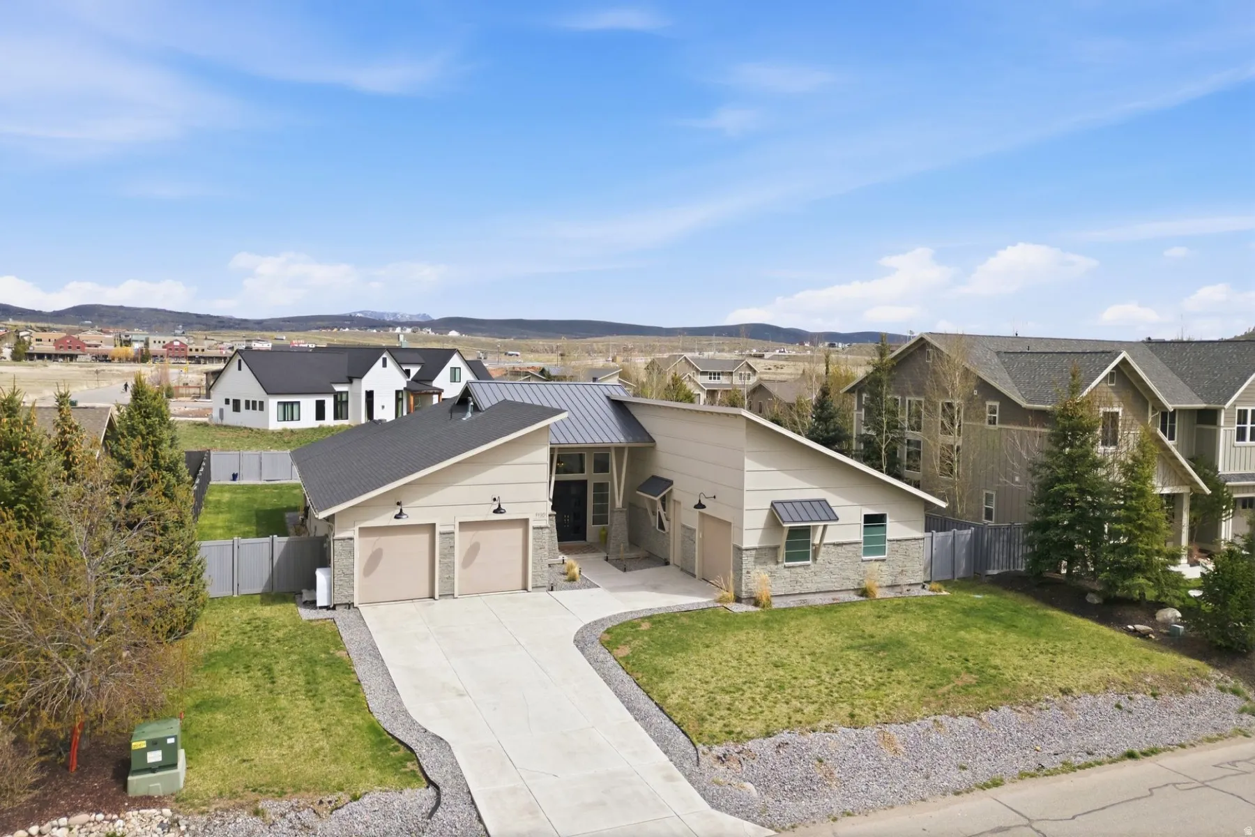 View of front of house featuring a garage, a residential view, driveway, a mountain view, and a metal roof