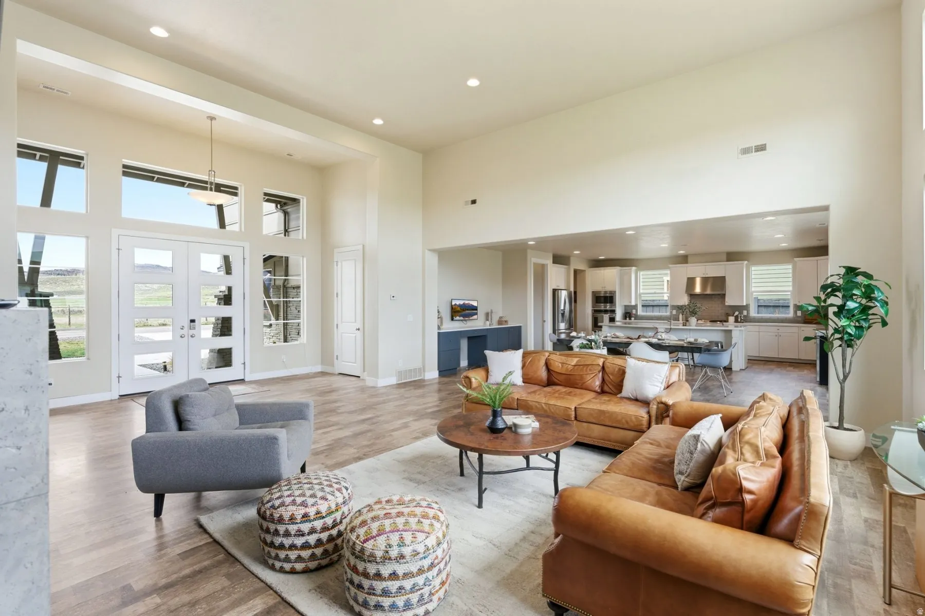 Living room featuring a high ceiling, light wood-style floors, recessed lighting, and french doors
