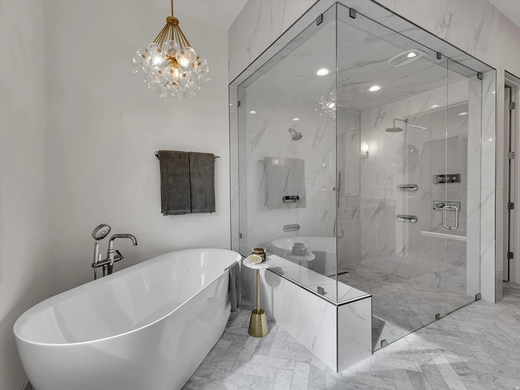 Full bath with a freestanding tub, light marble finish floors, hanging lights, and a marble finish shower