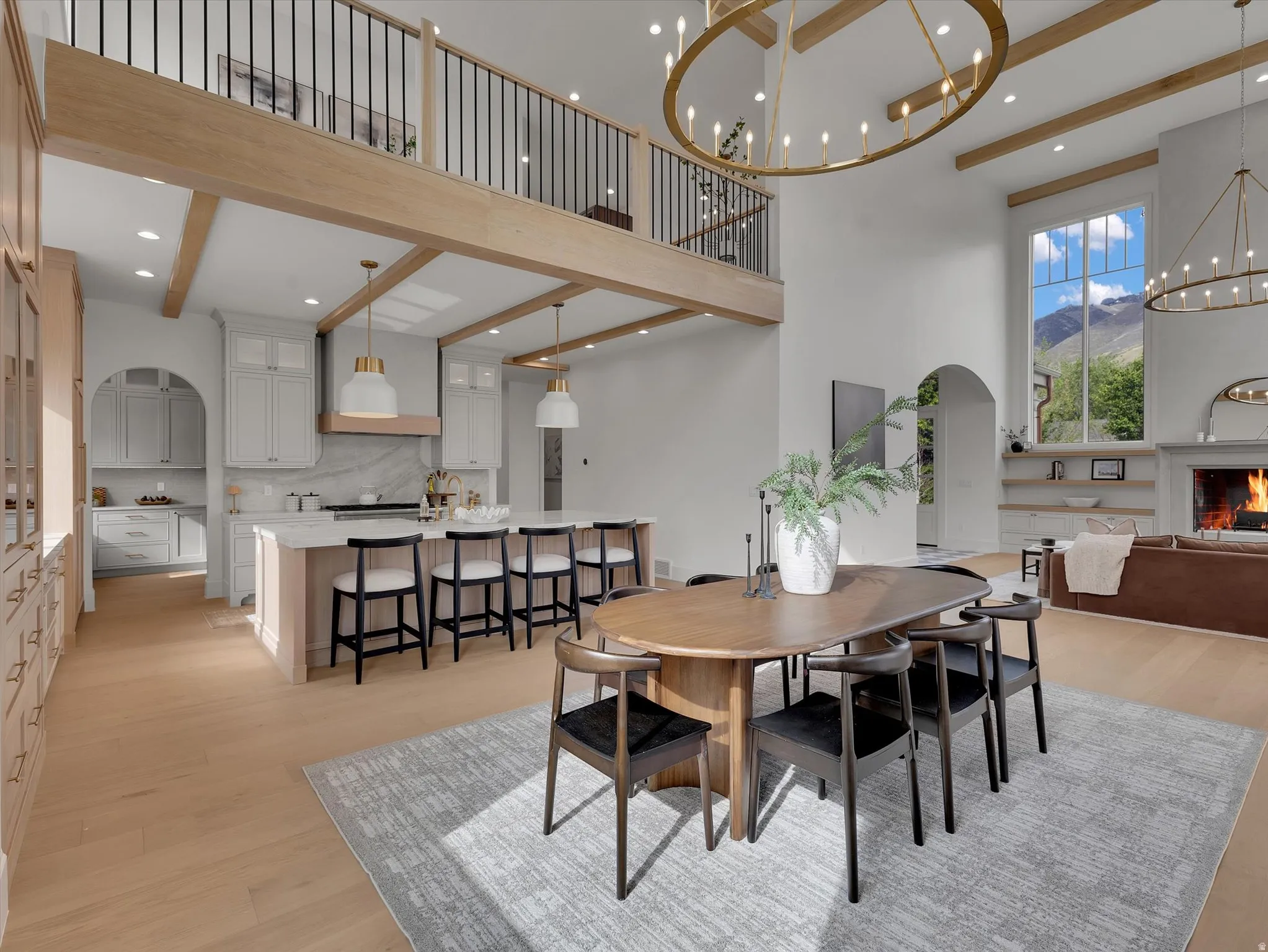 Dining area featuring light wood-style flooring, arched walkways, a chandelier, a mountain view, and a high ceiling