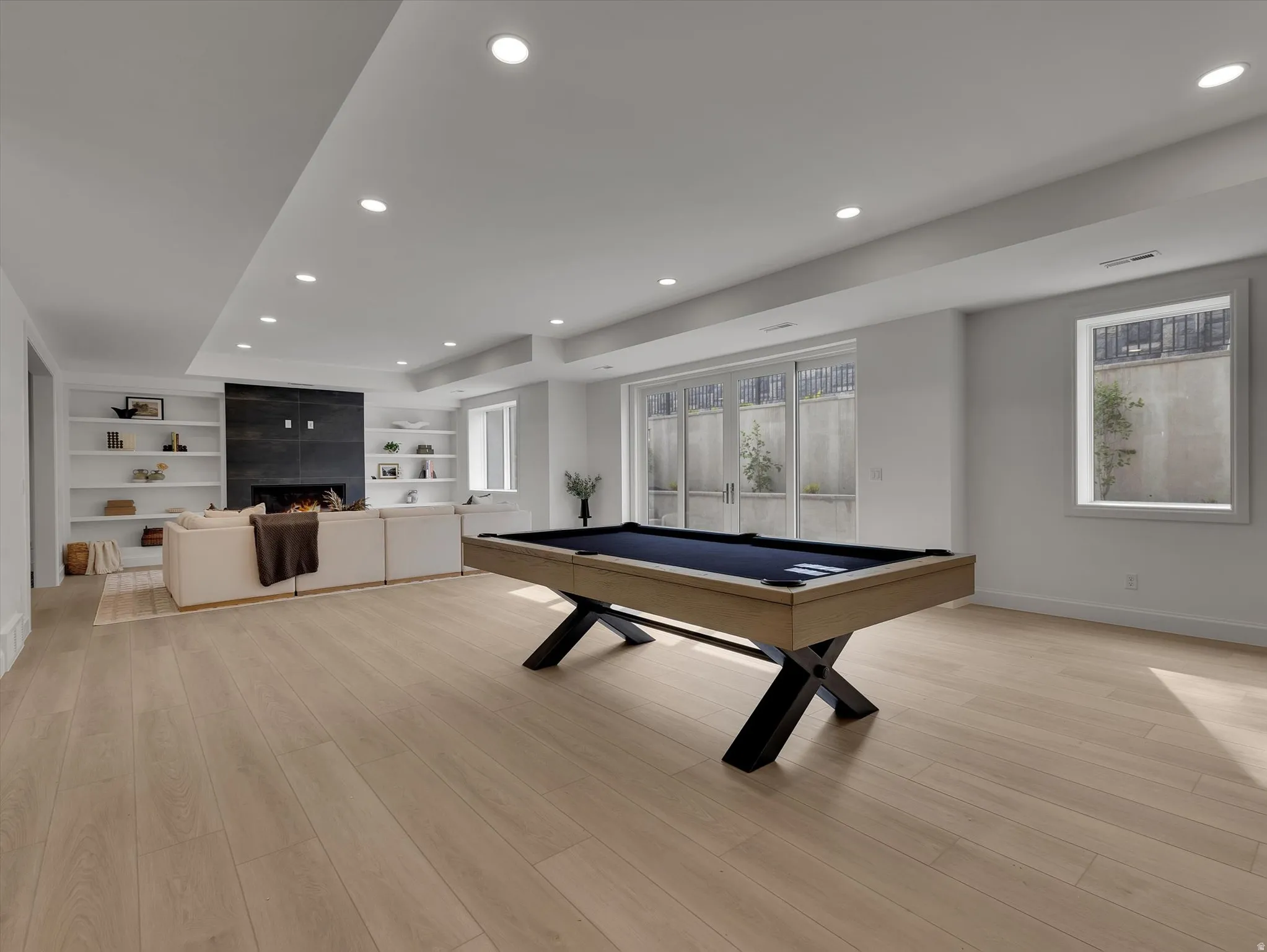 Rec room featuring light wood finished floors, pool table, a fireplace, recessed lighting, and built in shelves