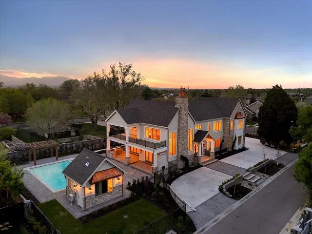 Rear view of house with a fenced backyard, stone siding, a patio, and a balcony