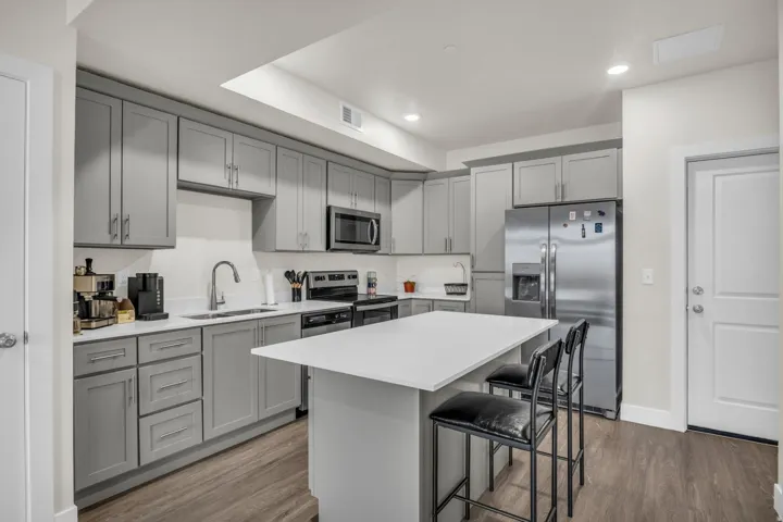 Kitchen featuring gray cabinets, stainless steel appliances, dark wood finished floors, a center island, and recessed lighting
