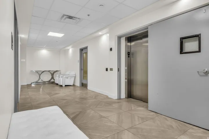 Corridor featuring a drop ceiling and elevator