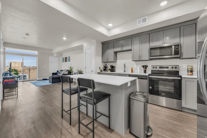 Kitchen featuring gray cabinetry, stainless steel appliances, open floor plan, a breakfast bar, and light wood-style floors