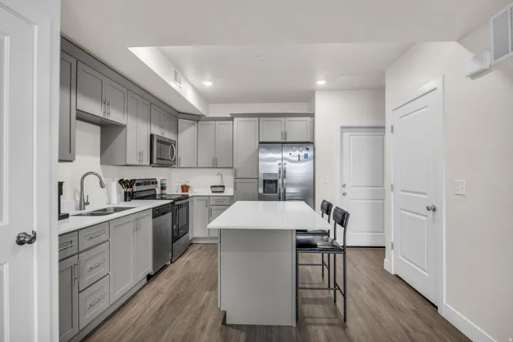Kitchen featuring gray cabinetry, a center island, dark wood-type flooring, a kitchen bar, and recessed lighting