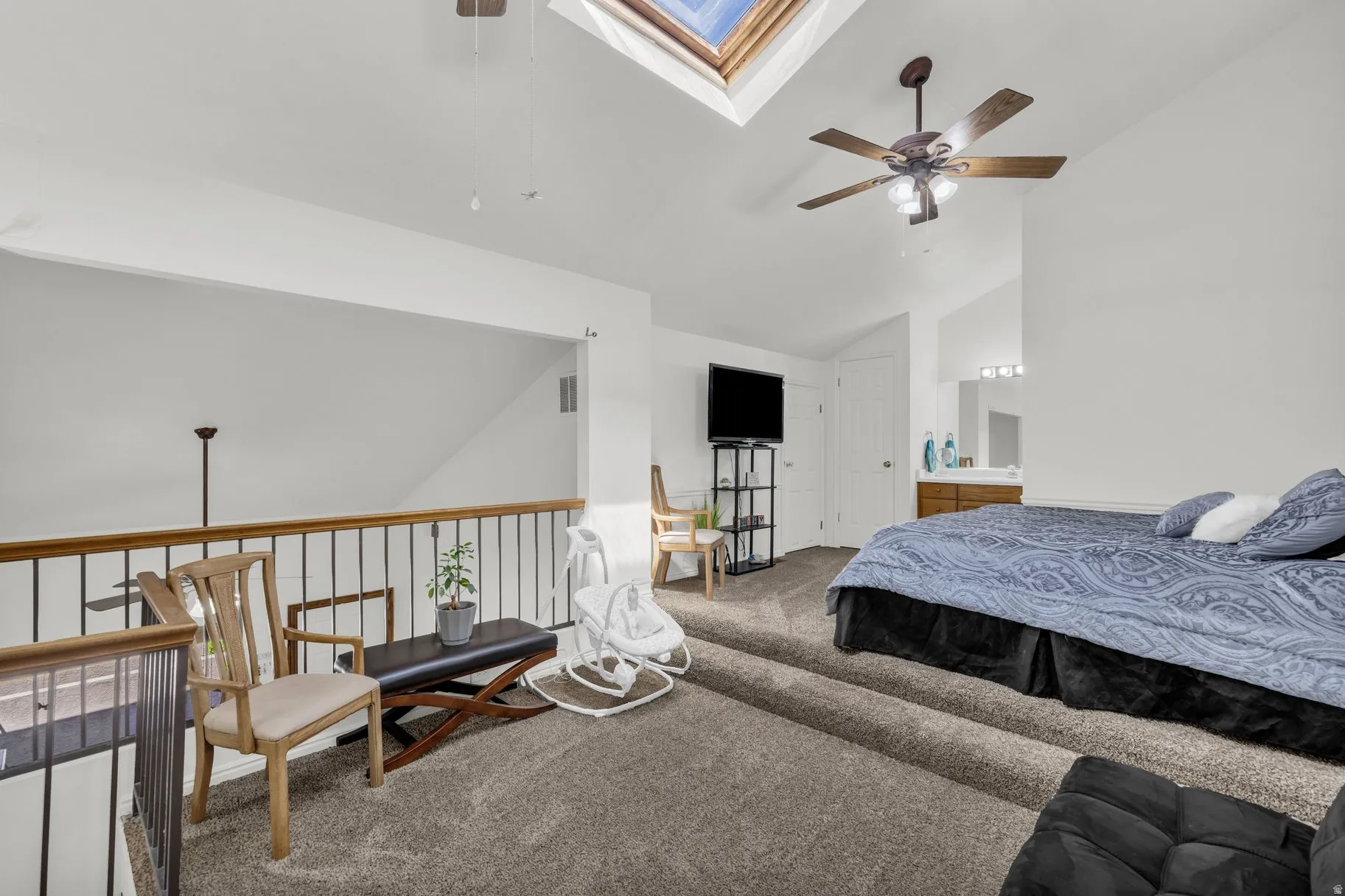 Carpeted bedroom with a skylight, lofted ceiling, and a ceiling fan