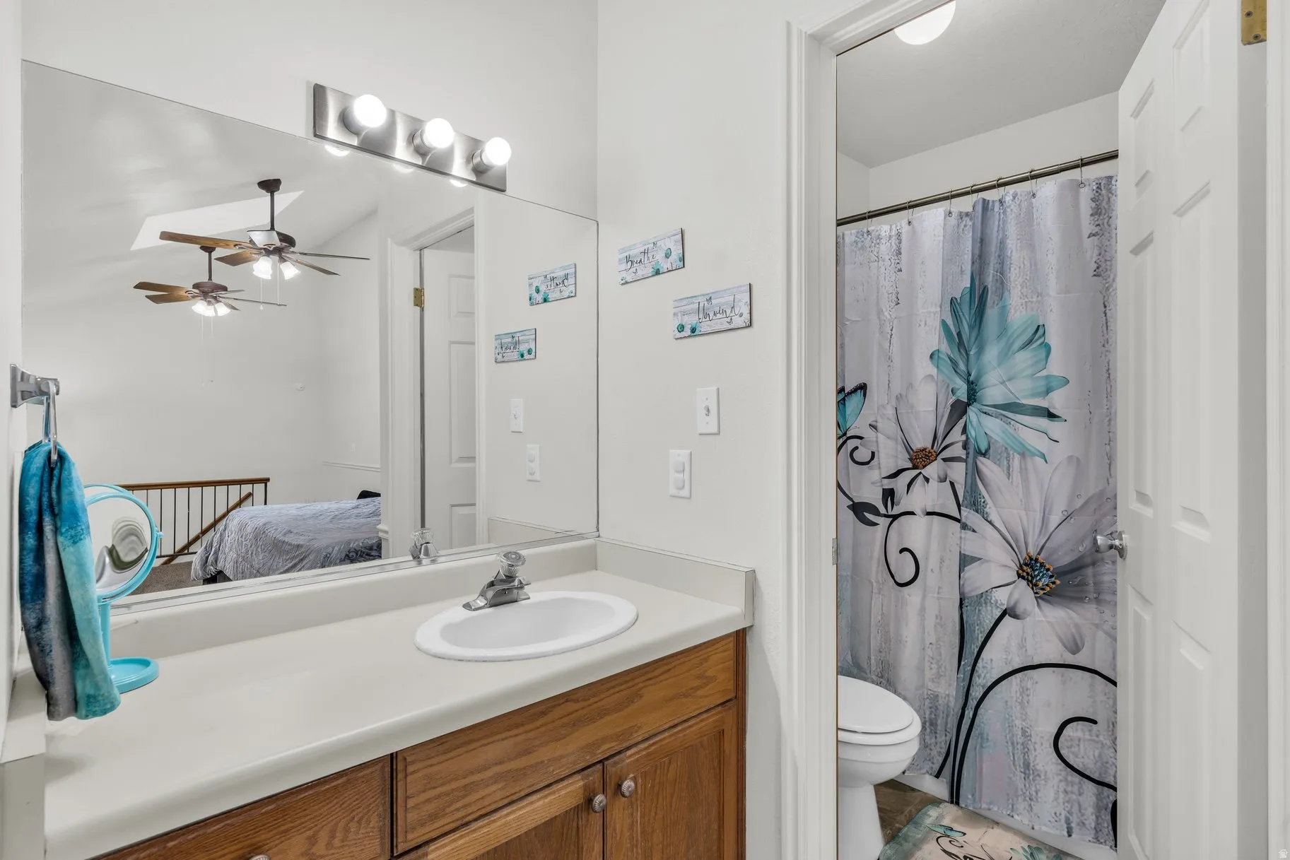 Ensuite bathroom featuring vanity, curtained shower, and ceiling fan