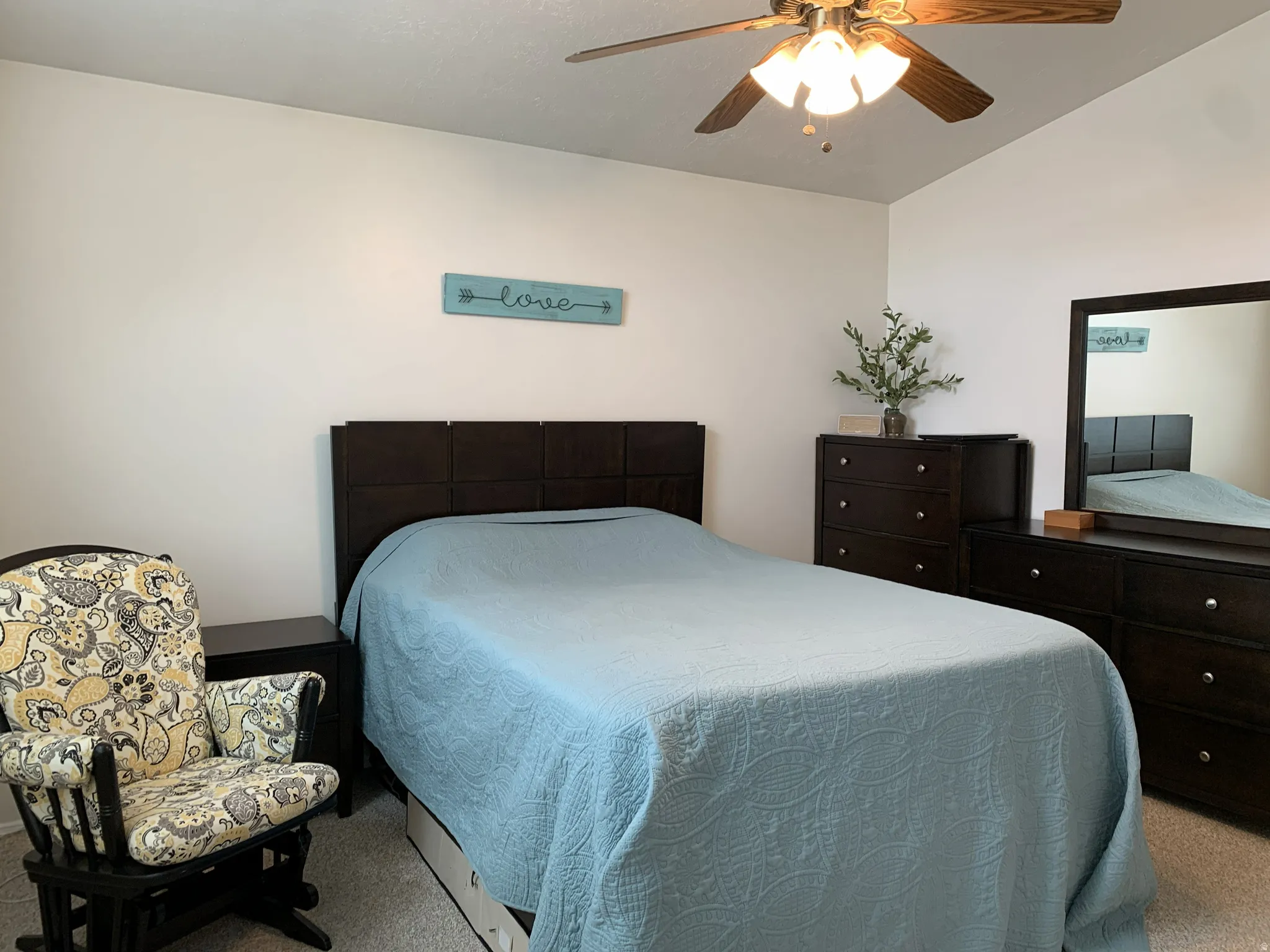 Carpeted bedroom with a ceiling fan and lofted ceiling