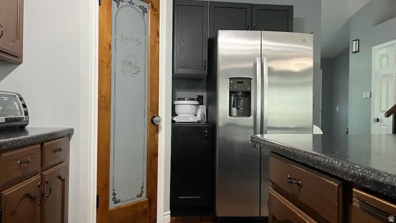 Kitchen with stainless steel fridge with ice dispenser and dark stone counters