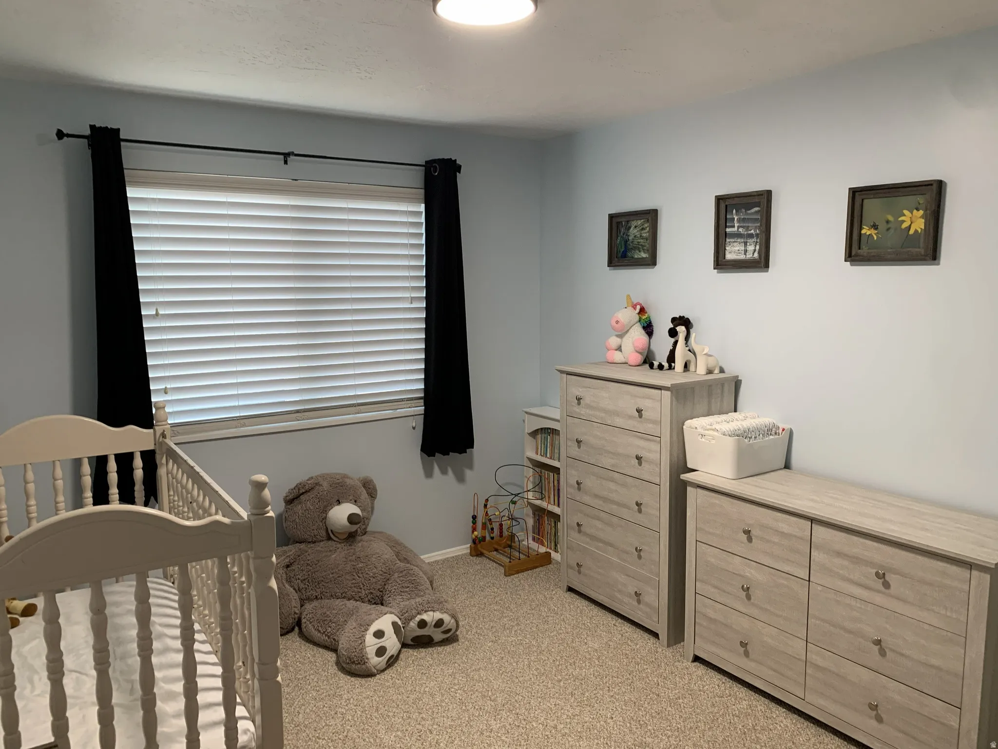 Bedroom featuring a nursery area and light carpet