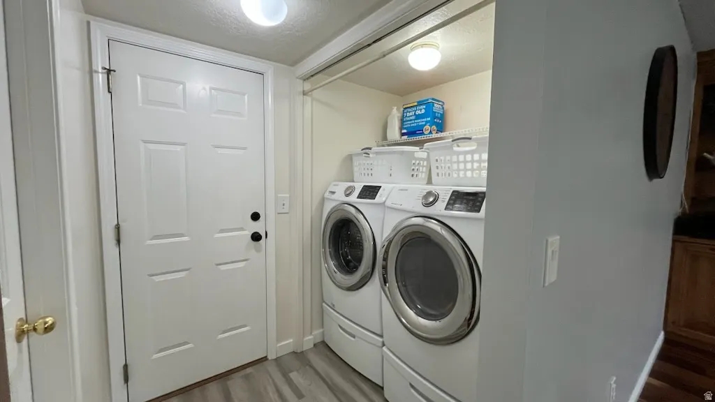 Laundry room with a textured ceiling, LVP style floors, and washing machine and clothes dryer