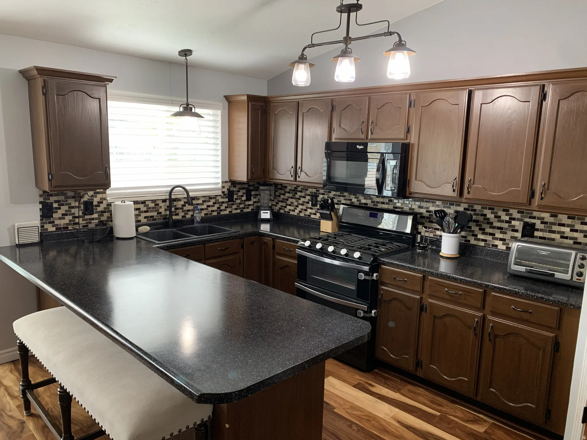 Kitchen featuring a breakfast bar, dark countertops, range with two ovens, a peninsula, and black microwave