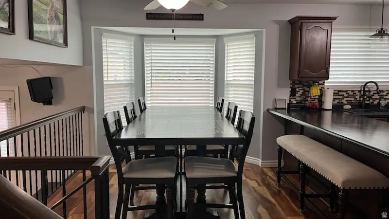 Dining space with dark wood finished floors, ceiling fan, and plenty of natural light