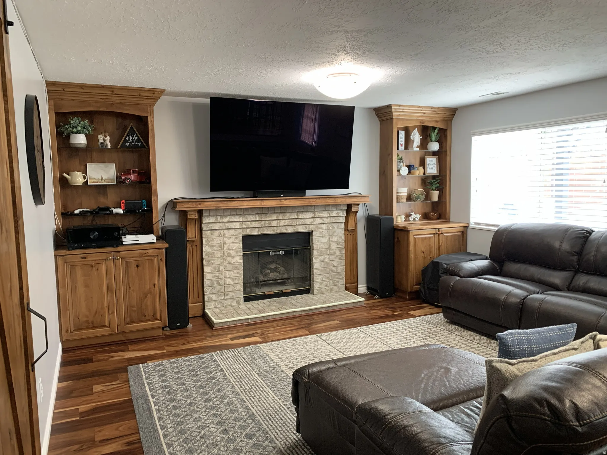 Living room featuring a textured ceiling, hardwood floors, and a glass covered fireplace