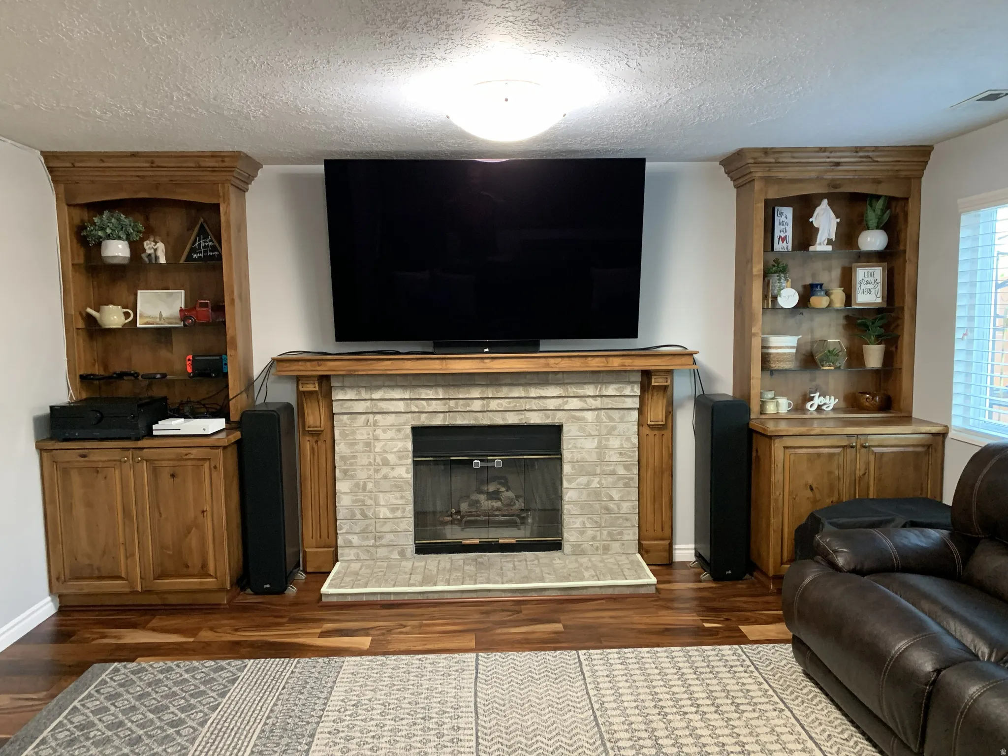 Living area featuring a textured ceiling, hardwood floors, and a fireplace