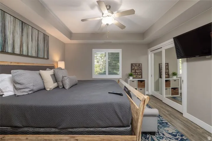 Master Bedroom featuring wood finished floors, a ceiling fan, a tray ceiling, and access to outside