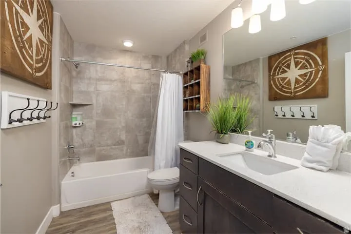 Bathroom featuring vanity, shower / bathtub combination with curtain, and wood finished floors